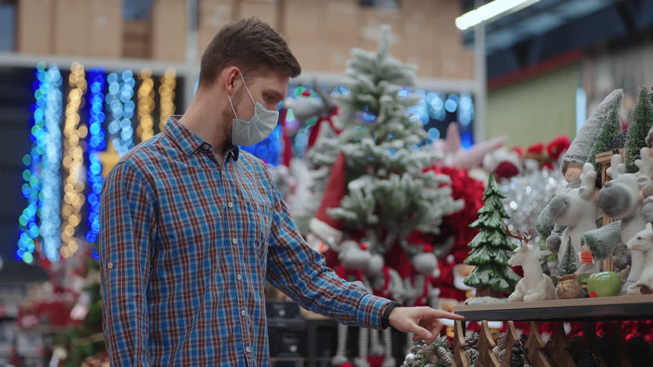 compras en pandemia y cuarentena. un hombre con una máscara protectora en una joyería y guirnaldas con juguetes para árboles de navidad y en casa. guirnaldas navideñas y decoración.