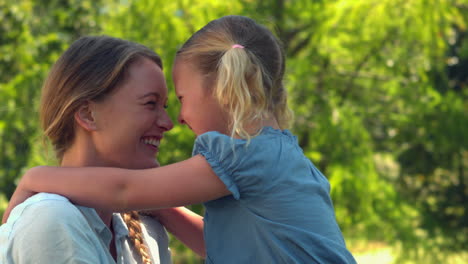 Young-mother-giving-her-daughter-a-hug-in-the-park