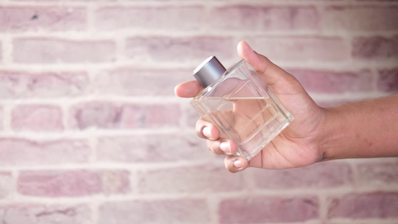 La mano che tiene una bottiglia di profumo
