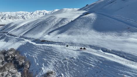 Mountains-at-winter-time-,-riding-horses-aerial-video