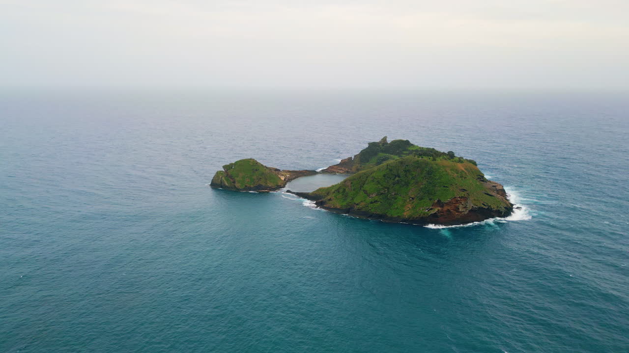 isla abandonada bañada por el agua del océano vista aérea. paisaje verde en medio del mar