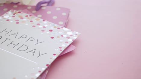 tarjeta de cumpleaños con bolsa de regalos rosada y flores