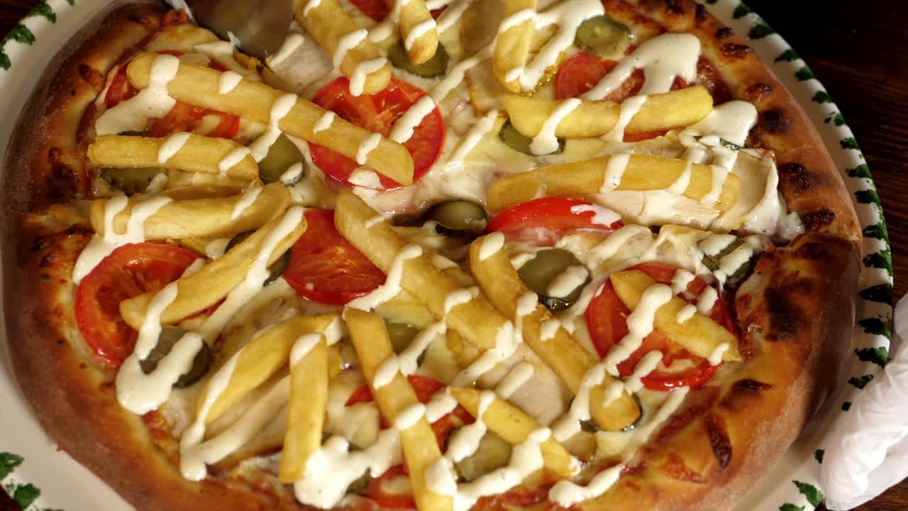 한 손이 롤러 피자 커터로 김 피자를 잘라내고 있다