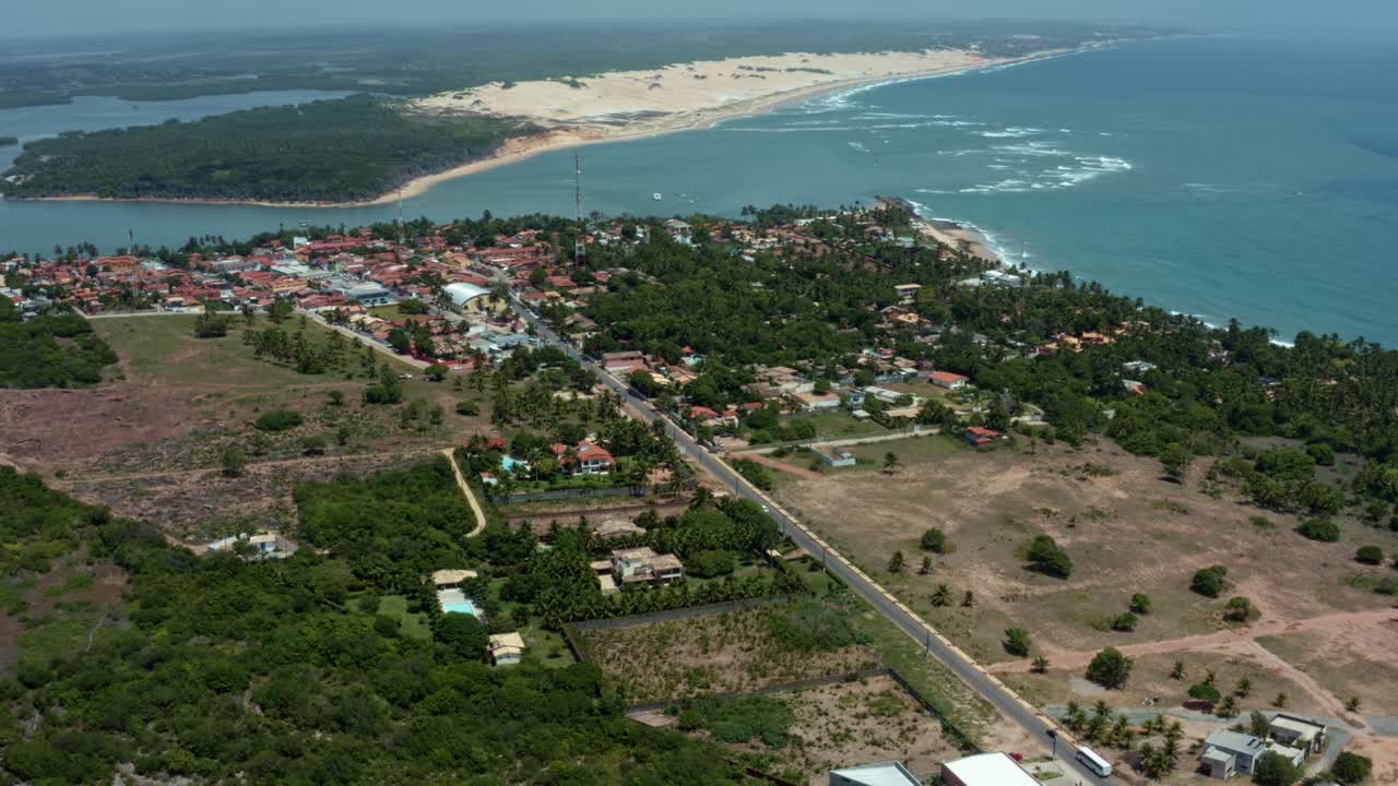 Tilt up aerial drone extreme wide shot of the tropical beach town of Tibau do Sul in Rio Grande do Norte, Brazil with the Malemb&aacute; Sand Dunes, Atlantic Ocean, and Guara&iacute;ras Lagoon in the background