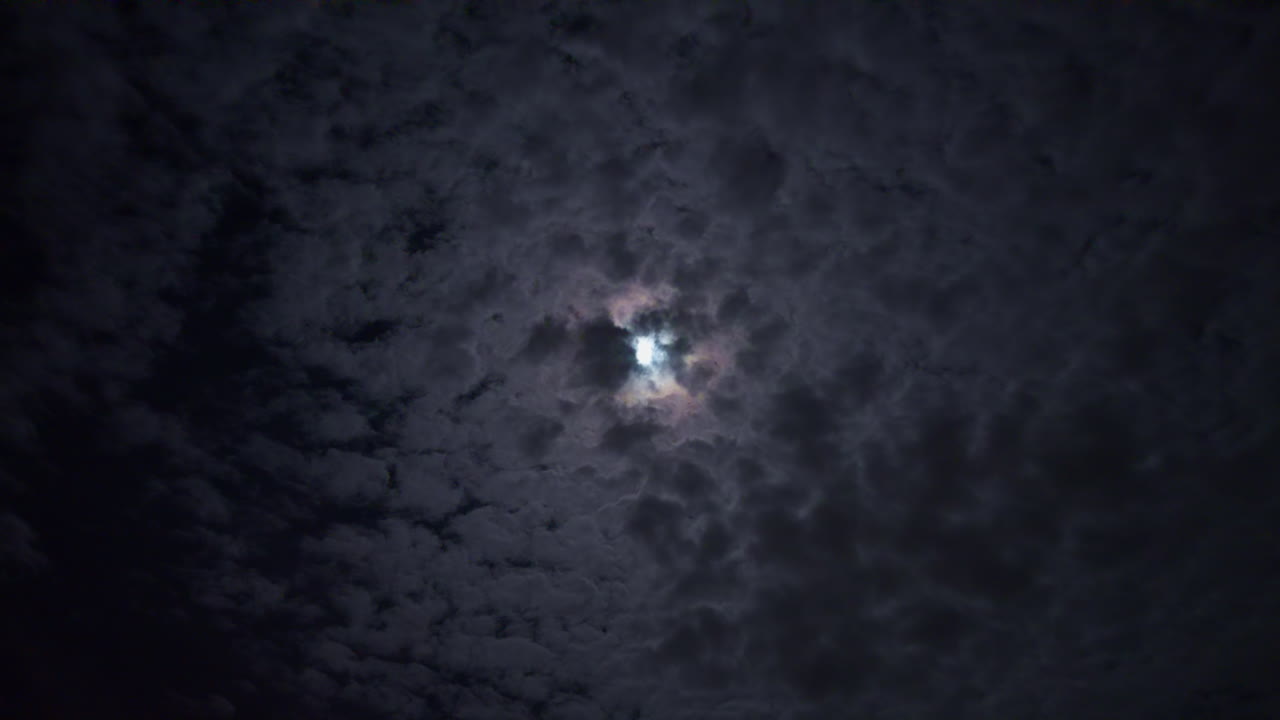 Moon in the dark night sky with fast moving clouds, moonlight beyond skies with dark ambient atmosphere