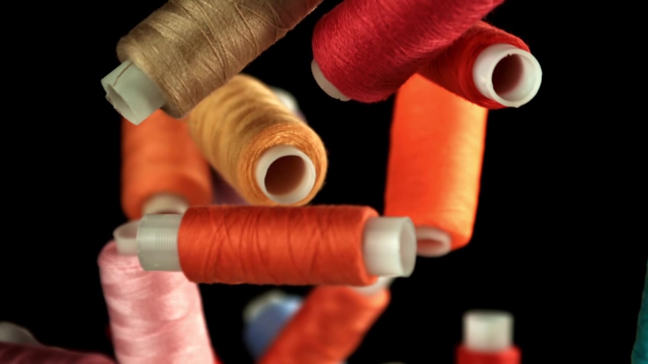 Colorful Sewing Threads Falling in Slow Motion on Black Background