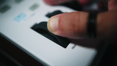 close-up of a hand adjusting a pitch control knob on a music production device