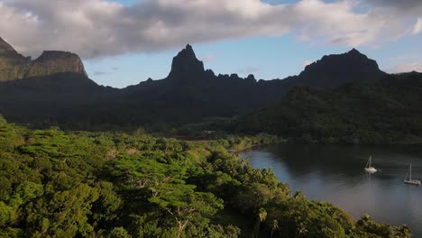 barcos de vela anclados en el espectacular destino de la isla de moorea en la polinesia francesa con exuberantes bosques y altos picos montañosos que rodean una bahía aislada para un anclaje seguro