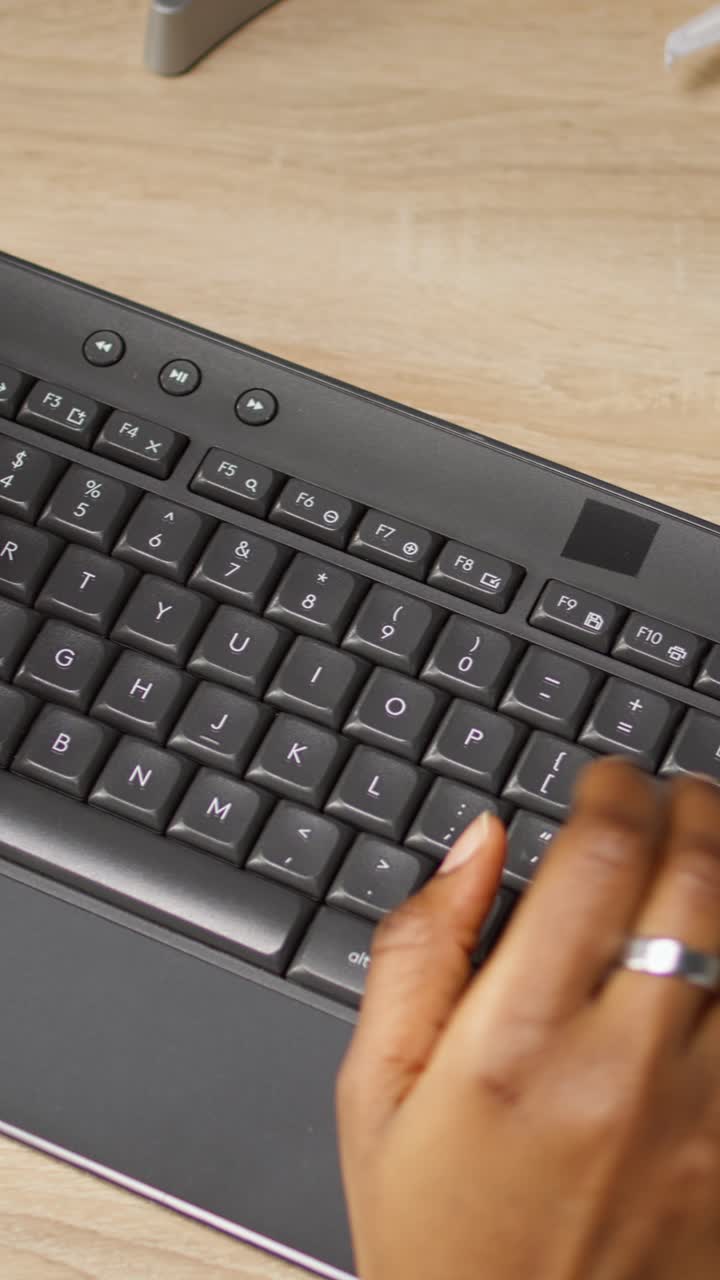 Vertical video Person at home office desk typing on PC keyboard next to coffee mug, close up