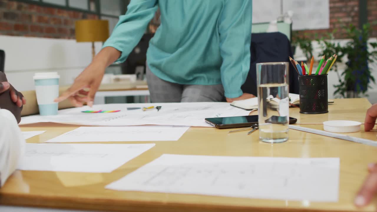 arquitectos diversos felices mirando planos arquitectónicos y discutiendo el trabajo en la oficina