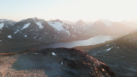 aerial of stunning mountain landscape with lake, peaks covered with snow, capture location norway, 4k