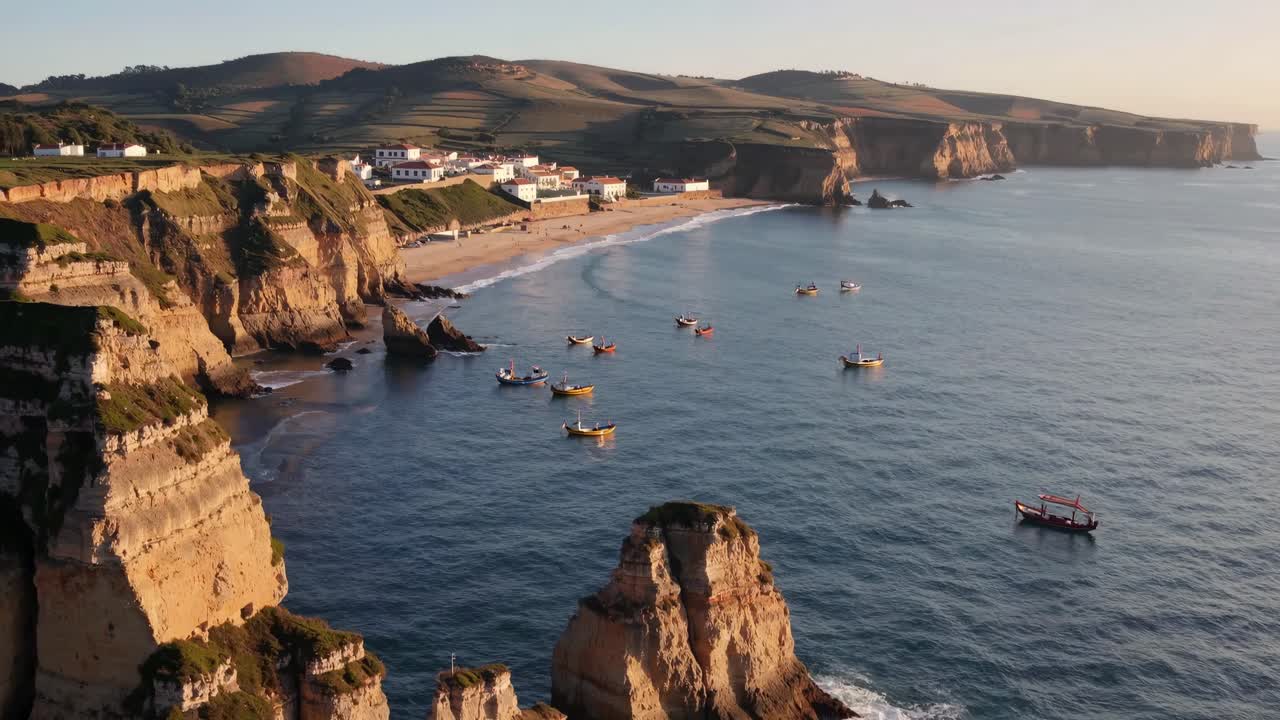 Aerial video captures a serene coastal landscape with cliffs, boats, and a beachside village