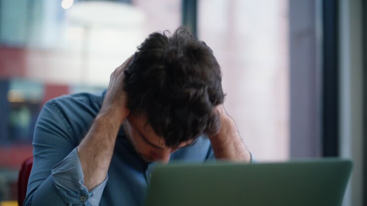 Primo piano di un freelance preoccupato che fa una telefonata seduto alla scrivania di casa.