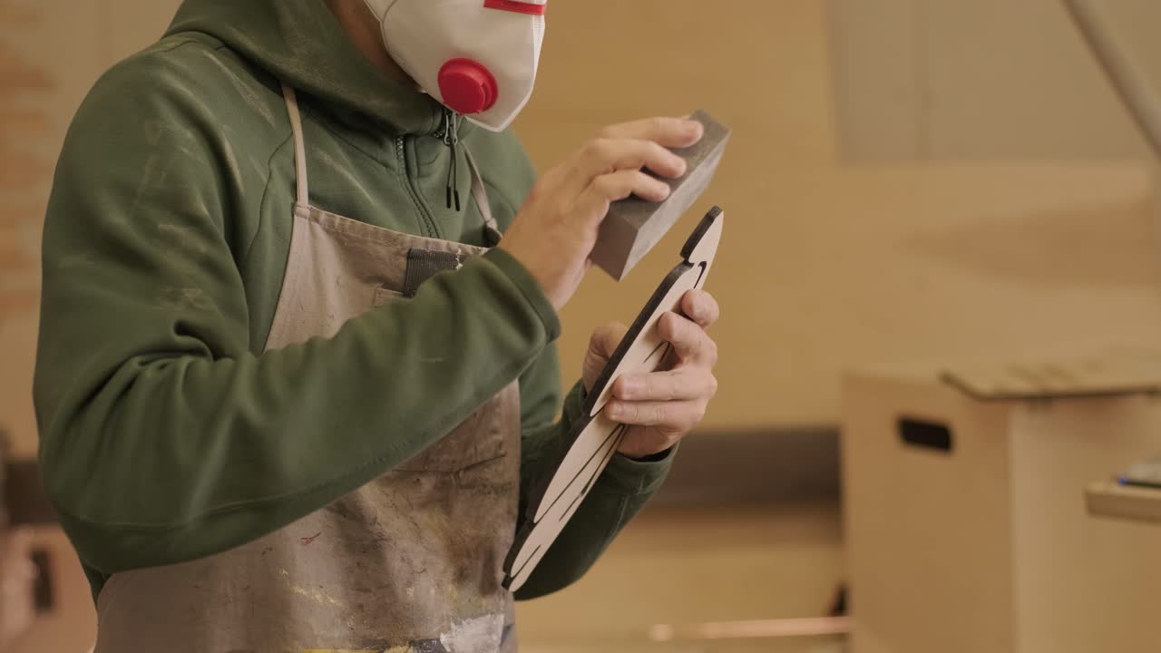 목수 한 명 이 나무 한 조각 을 가공 하고 있다. 그 조각 은 샌드 페이퍼 를 사용 하여 cnc 레이저 기계 로 만든 플라이우드 제품 이다.