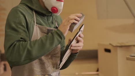 un carpintero está moliendo una pieza de madera, un producto de madera contrachapada hecho en una máquina láser cnc usando papel de arena