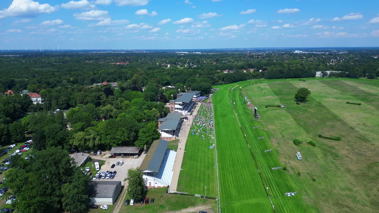horse racing track with spectators enjoying the competition on a sunny summer day. Smooth aerial view flight drone shot footage from above