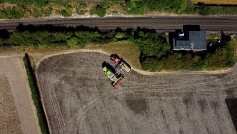 aerial footage of a combine harvester feeding produce into the trailer of a tractor