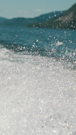 water roars and foams on lake while boat moves. majestic landscape of water massif on summer day. shiny white splashes rises high into air above body of water slow motion