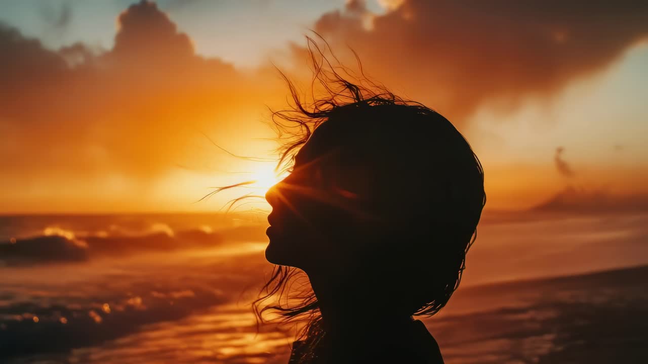 Silhouette of a person at sunset on a beach, captured in profile