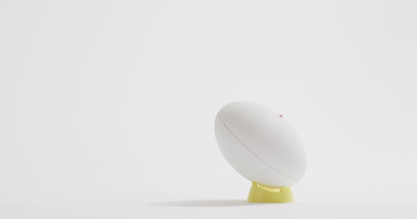 White rugby ball on kicking tee on white background with copy space, slow motion