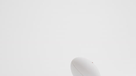 white rugby ball on kicking tee on white background with copy space, slow motion