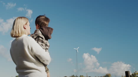 a woman shows her son a wind generator