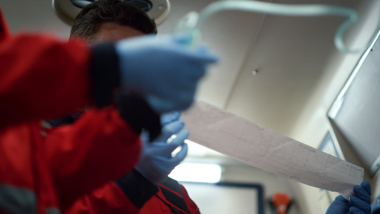 paramédicos dando primeros auxilios a un hombre. trabajadores médicos mirando el electrocardiograma