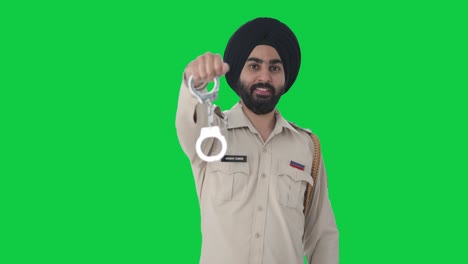 happy sikh indian police man posing with handcuffs green screen