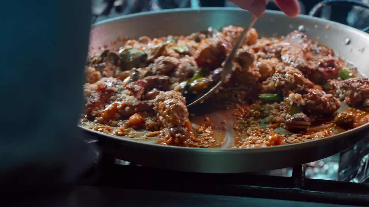 cocinero revuelve ingredientes para hacer paella española