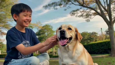 smiling young asian boy happily petting his labrador dog in a park.