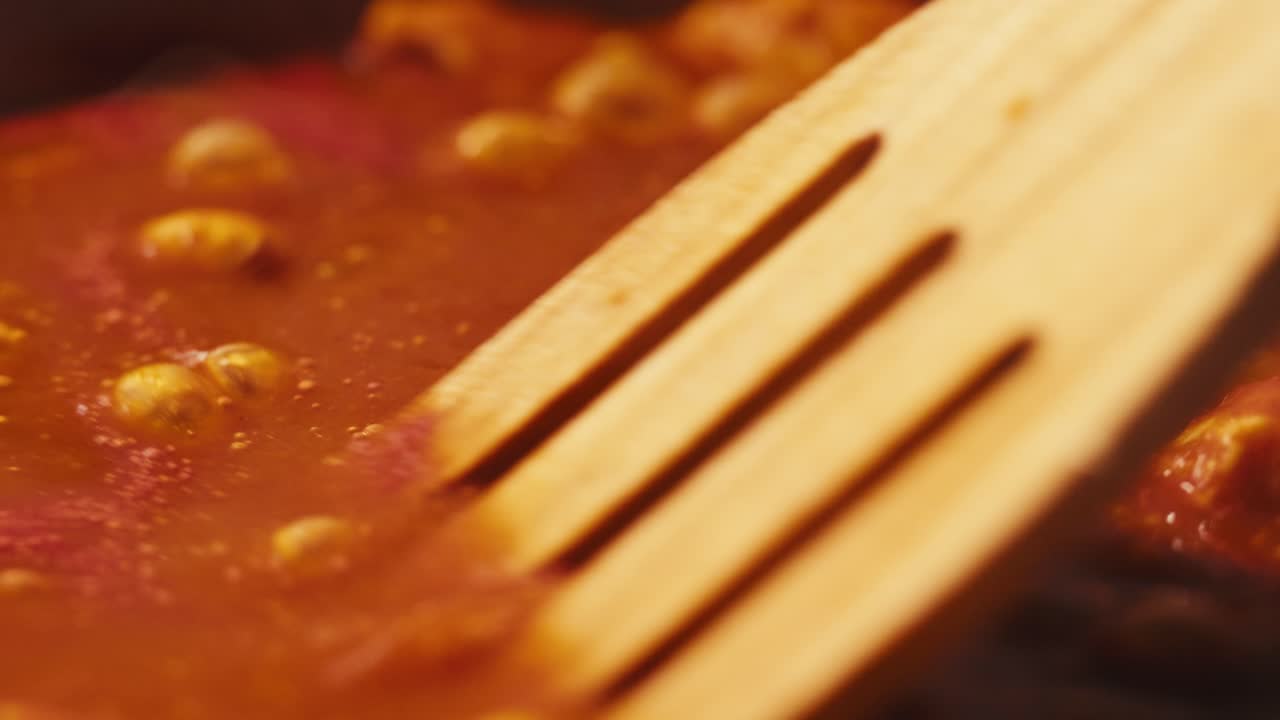 Chicken in tomato sauce is boiling on a frying pan with spices. Cooking tomato sauce curry with chicken fillet. Traditional Italian Mexican Asian dish. High quality studio shot for cafe, restaurant close up.