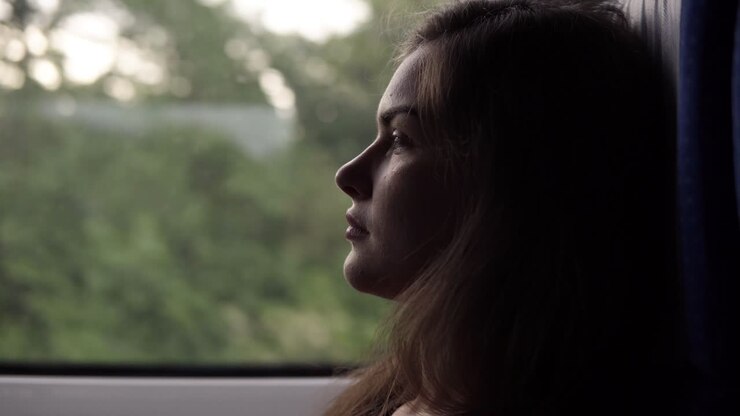 Side view of a relaxed, long haired beautiful girl riding on the speed train. Profile. Sitting near the window. Thoughtful, calm woman