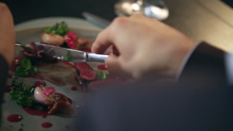 Male-hands-cutting-food-on-plate-in-restaurant.-Man-eating-meat-in-restaurant