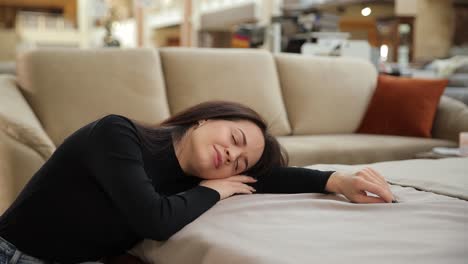 woman sleeps on a couch in a furniture store near bedding section in a furniture store a woman peacefully sleeps on a couch showcasing comfort and coziness