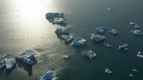 High-angle-view-of-iceberg-floating-in-Vatnajokull-national-park-lake.-Overhead-view-of-ice-block-formation-cracked-form-Breidamerkurjokull-glacier-drifting-in-Jokulsarlon-lagoon.-Climate-change