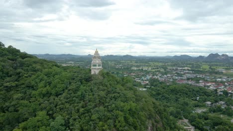 clock tower nestled on a hill amongst forest trees in thailand