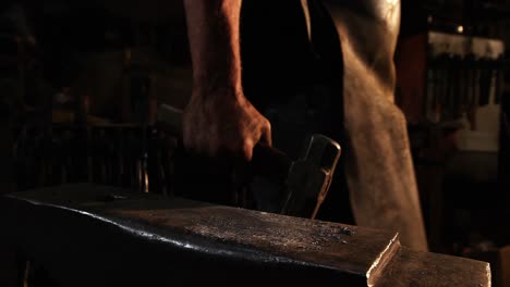 Mid-section-of-blacksmith-walking-with-hammer