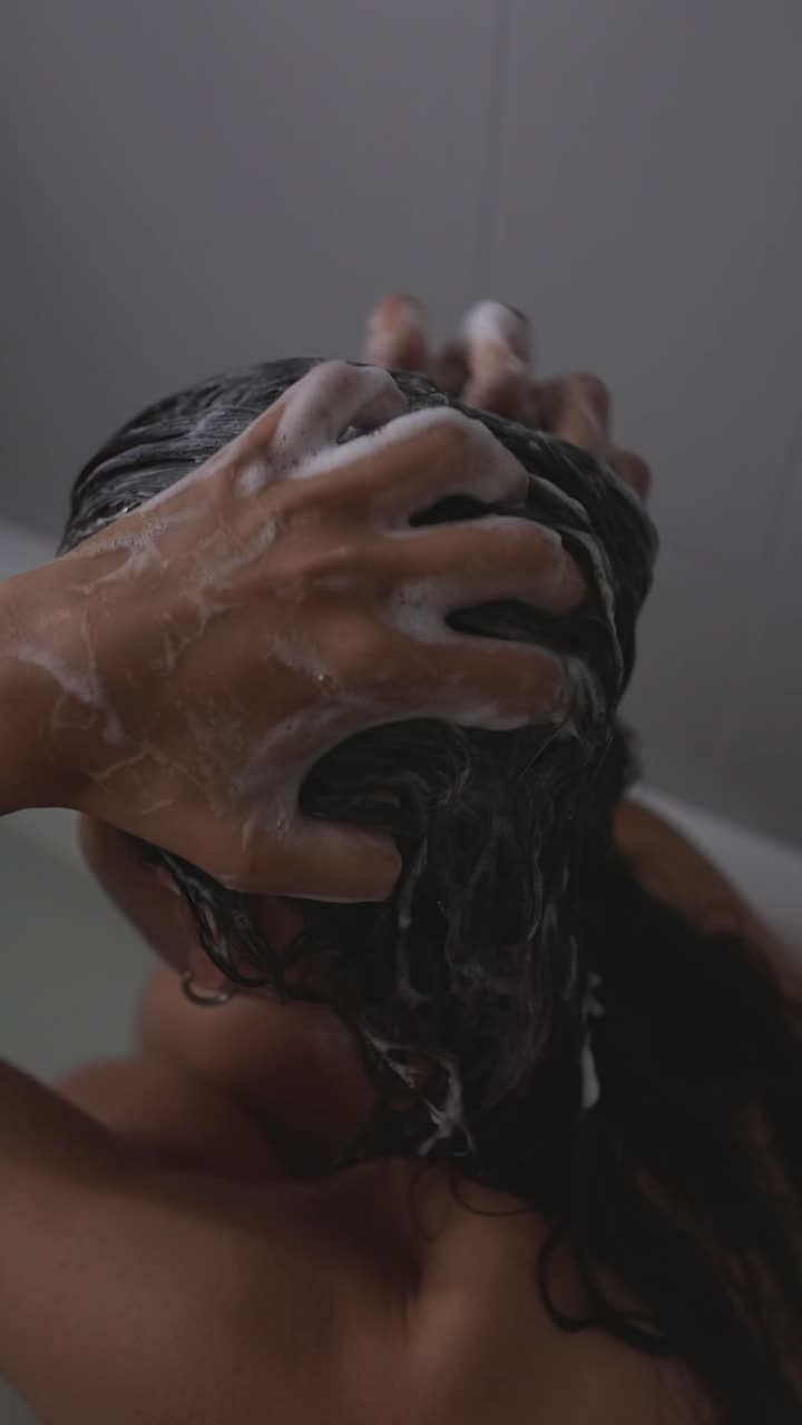 Donna che si lava i capelli con lo shampoo