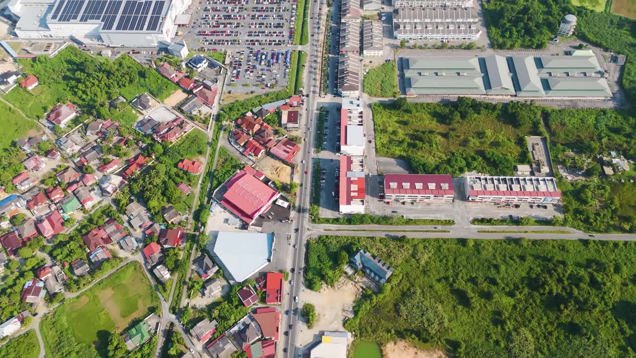 Top-down drone shot of Kota Bharu, Malaysia, capturing a busy traffic intersection surrounded by urban buildings, greenery, and mixed-use city areas in daylight