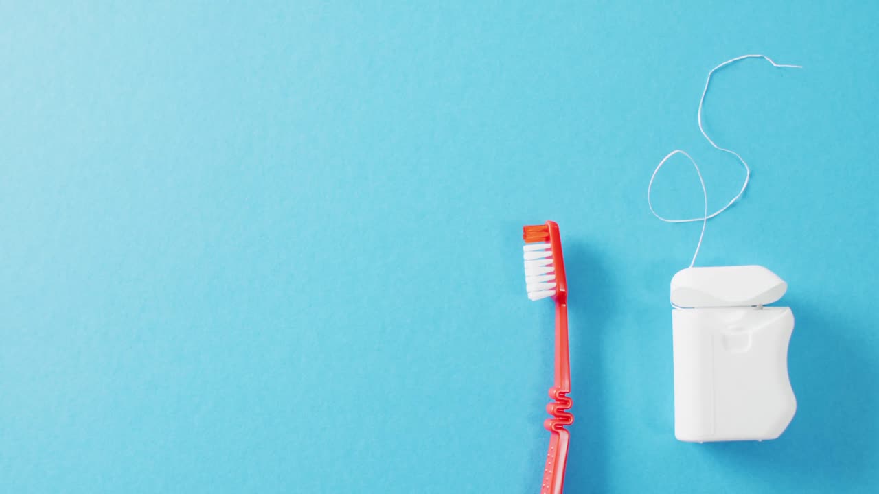 Video of close up of toothbrush and floss on blue background