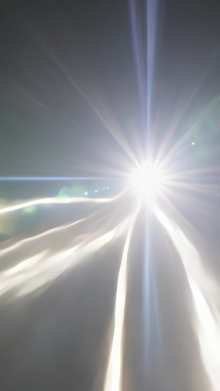 Vertical video: Approaching car headlamp brightening while phone filming on road, flare, copy space