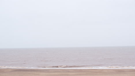 uk english norfolk beach seaside with fog and mist over sea panning left across coast