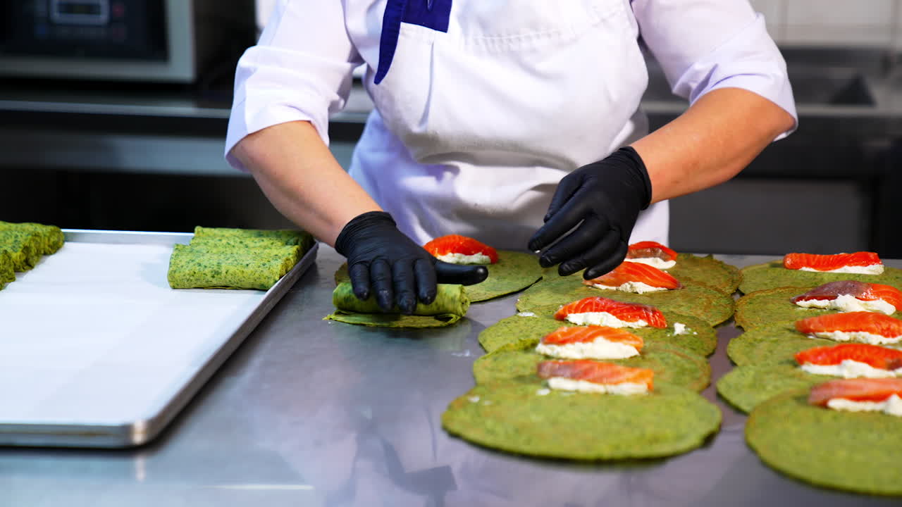 Thin pancakes with herbs are rolled with salmon and cottage cheese. Cook in black gloves puts the fish stuffing into crepes.