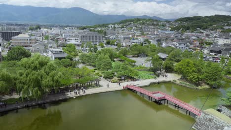 scenic aerial view of matsumoto castle park and cityscape, red bridge in historic japanese town