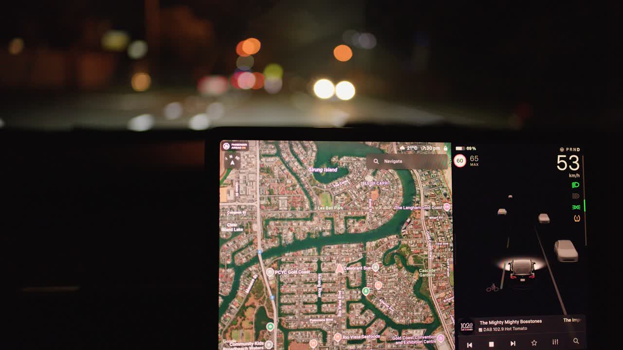 Interior view of car using digital navigation at night, dashboard screen illuminated, smooth forward motion
