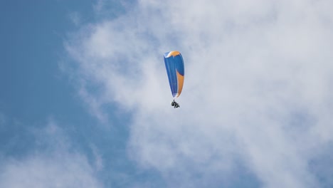 a lone paraglider descends from the skies on the parachute