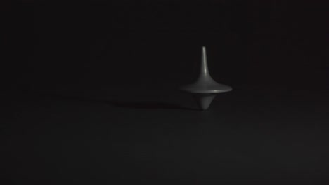 spinning top in motion without falling against black background, in black and white