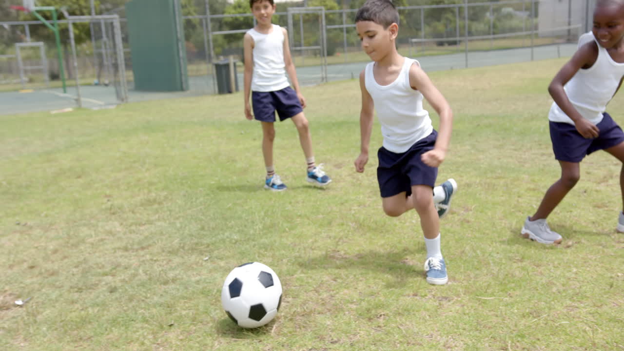 Playing soccer, three boys in school uniform enjoying outdoor activity on field