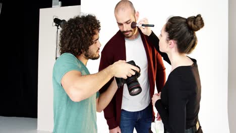 model getting face make-up while interacting with photographer