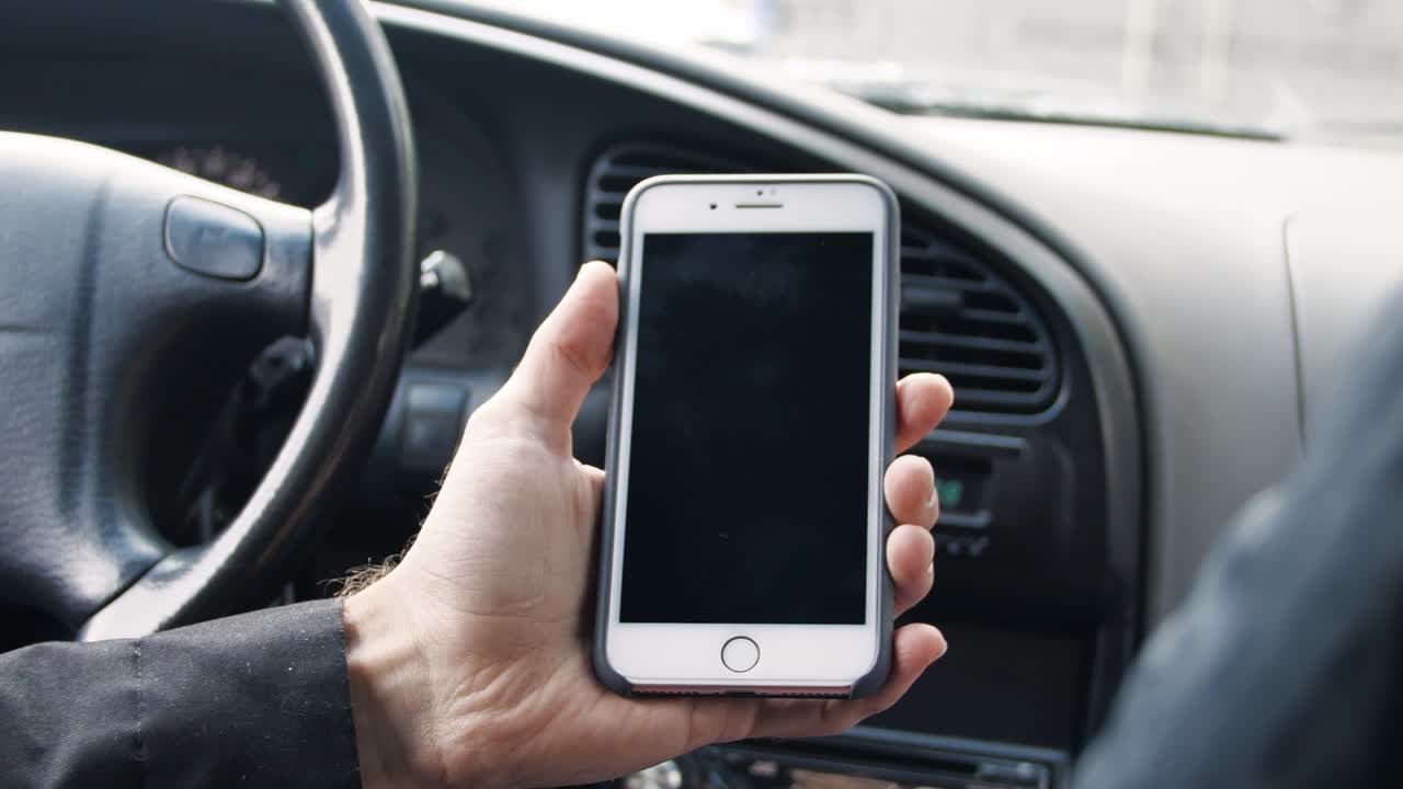 persona que utiliza un teléfono inteligente dentro de un automóvil